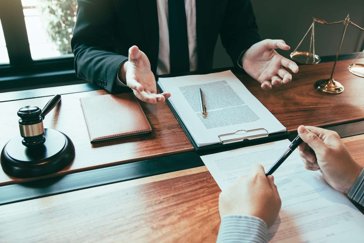 An attorney reviewing case documents with a client at a law office desk