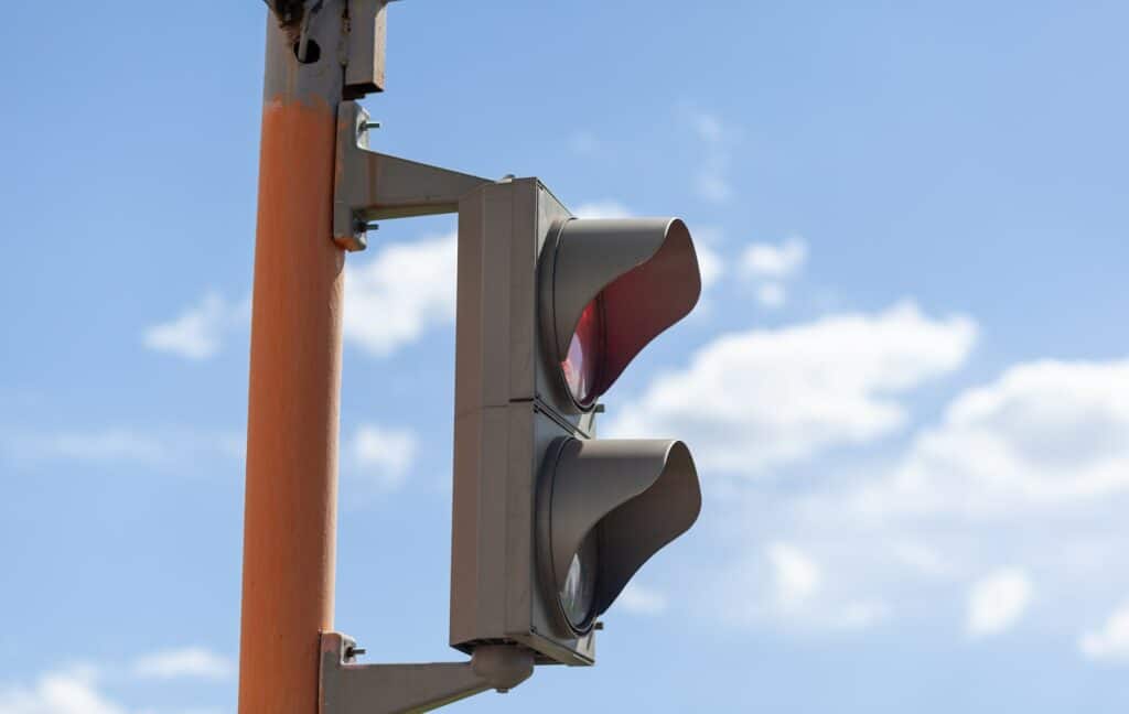 Red light on a pedestrian traffic light against a blue sky.